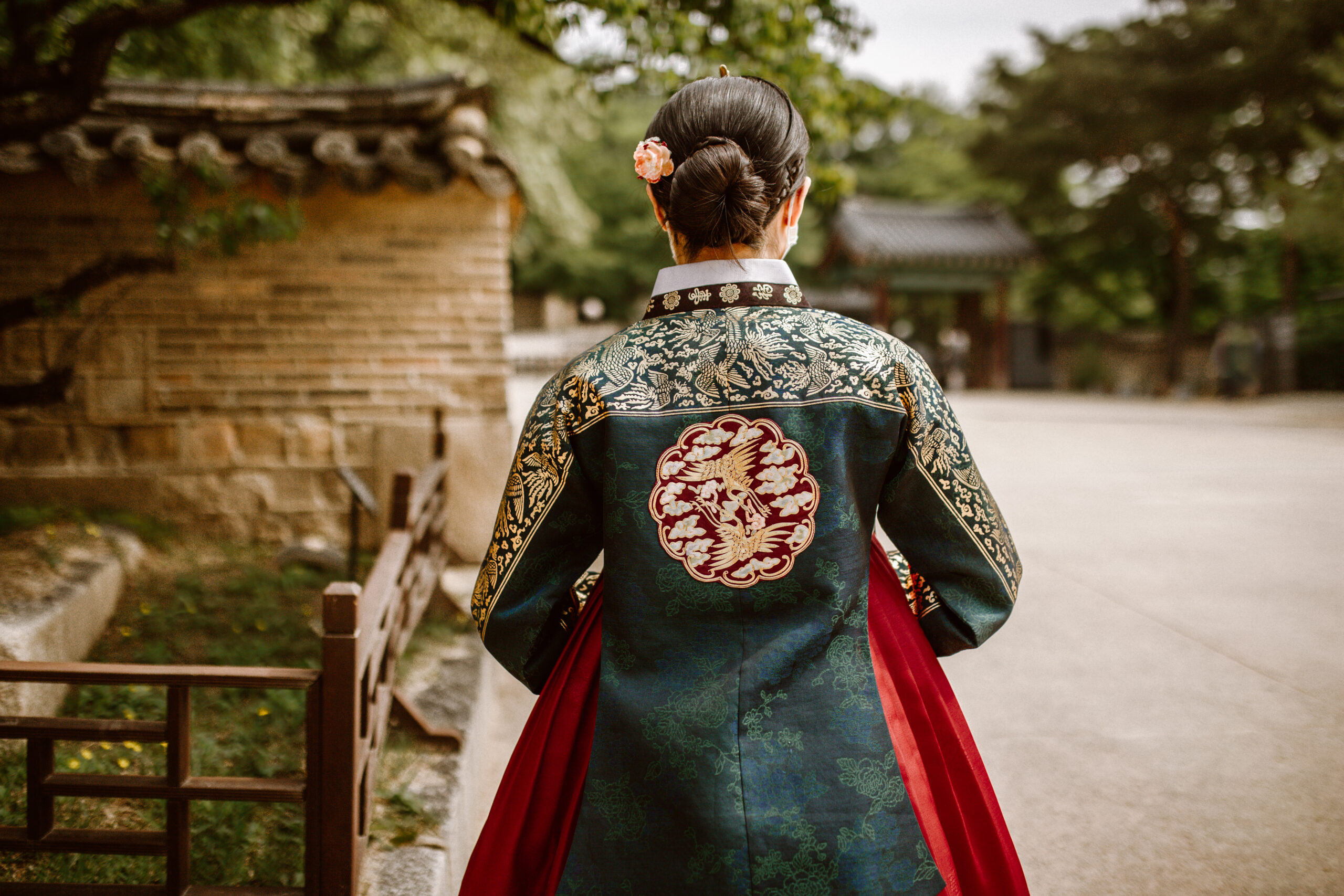 A back view of a woman wearing a green South Korean traditional embroidered dress