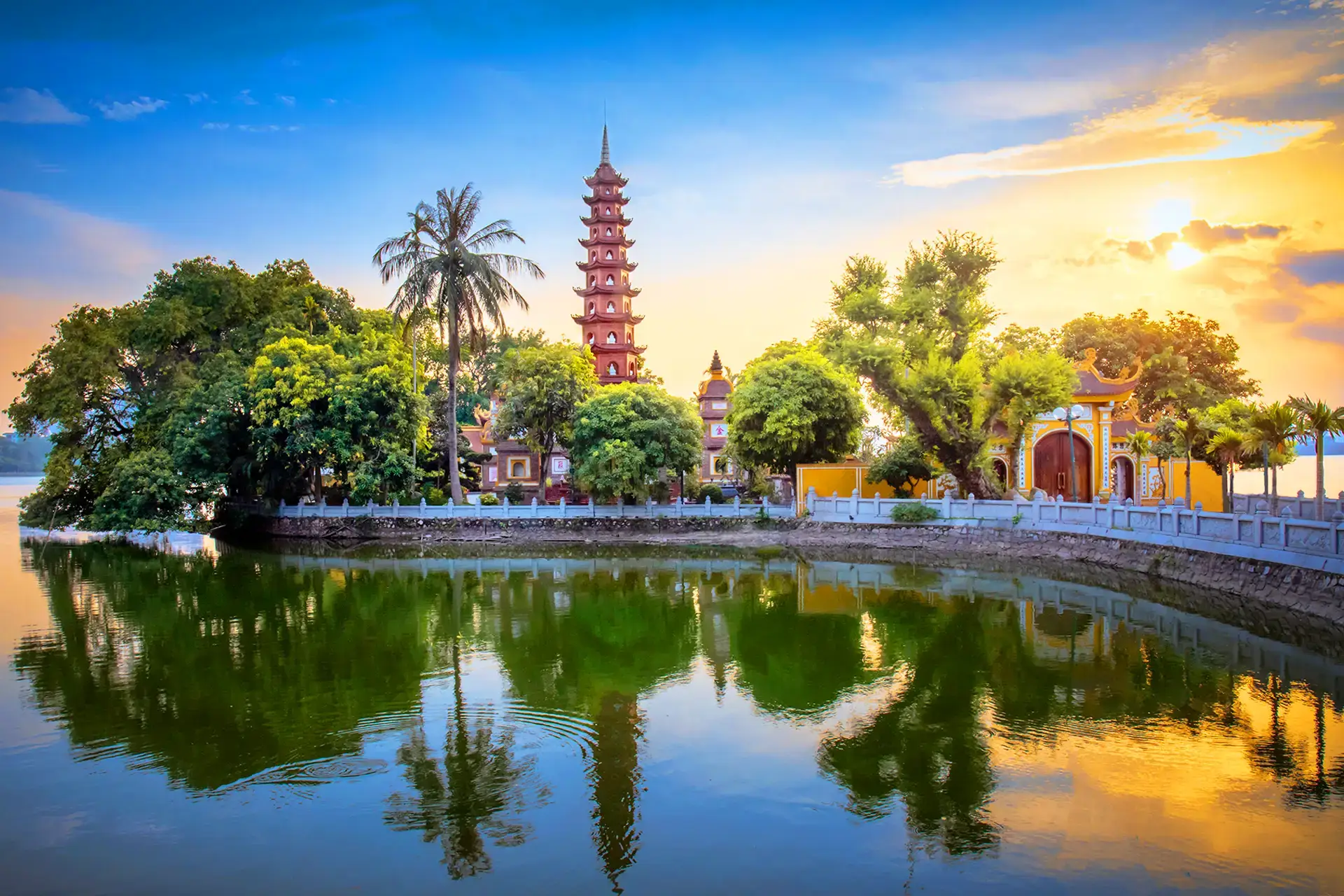 Calm evening scene of Hoan Kiem Lake reflecting city lights with Turtle Tower in Hanoi, Vietnam.