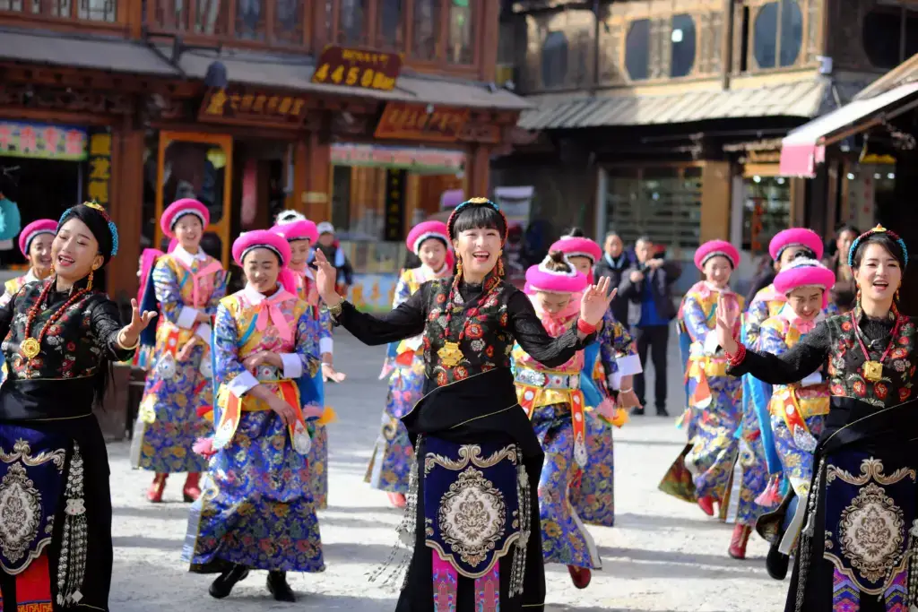Lebendige Straßenaufführung traditioneller Tänze in der Tibetischen Präfektur Diqing, China, die lebhafte kulturelle Kleidung präsentiert.